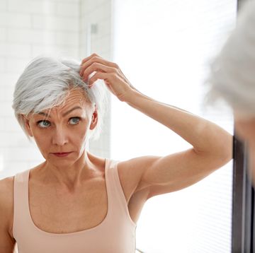 adult woman looking at her gray hair in the mirror