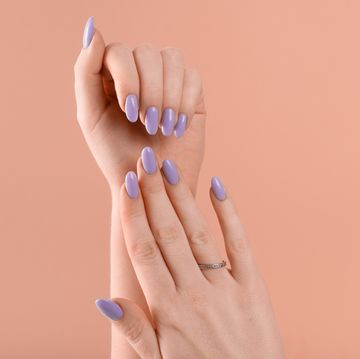 hands of a beautiful well groomed violet lavender nails gel polish on a beige background